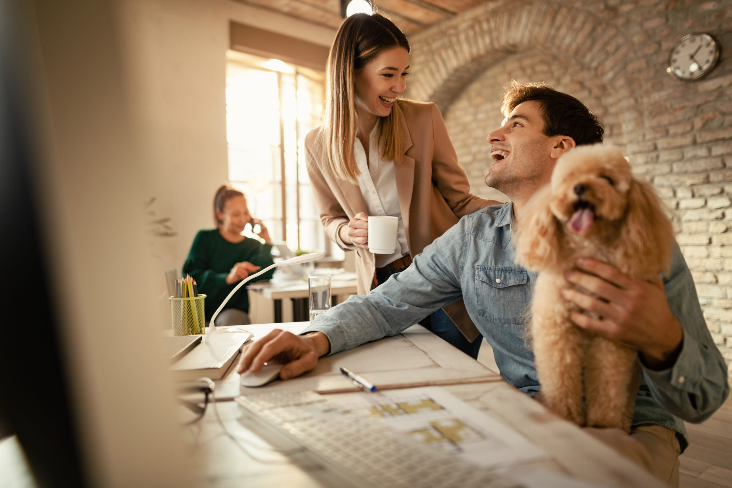happy-businessman-with-poodle-using-computer-while-talking-female-colleague-office-scaled.jpg